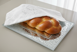 Close-up of glass challah tray with braided challahs