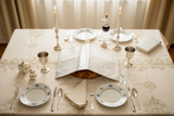 Overhead Shabbat table setting with white and silver cover